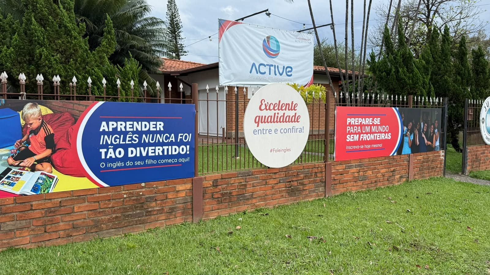 Fachada da Active Holambra, com a placa da escola e o jardim na entrada